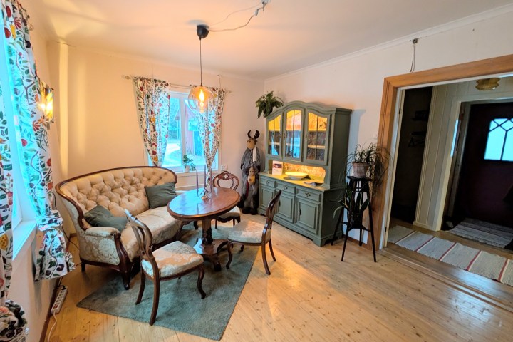 Cozy dining room with floral curtains, vintage furniture, and a green cabinet.